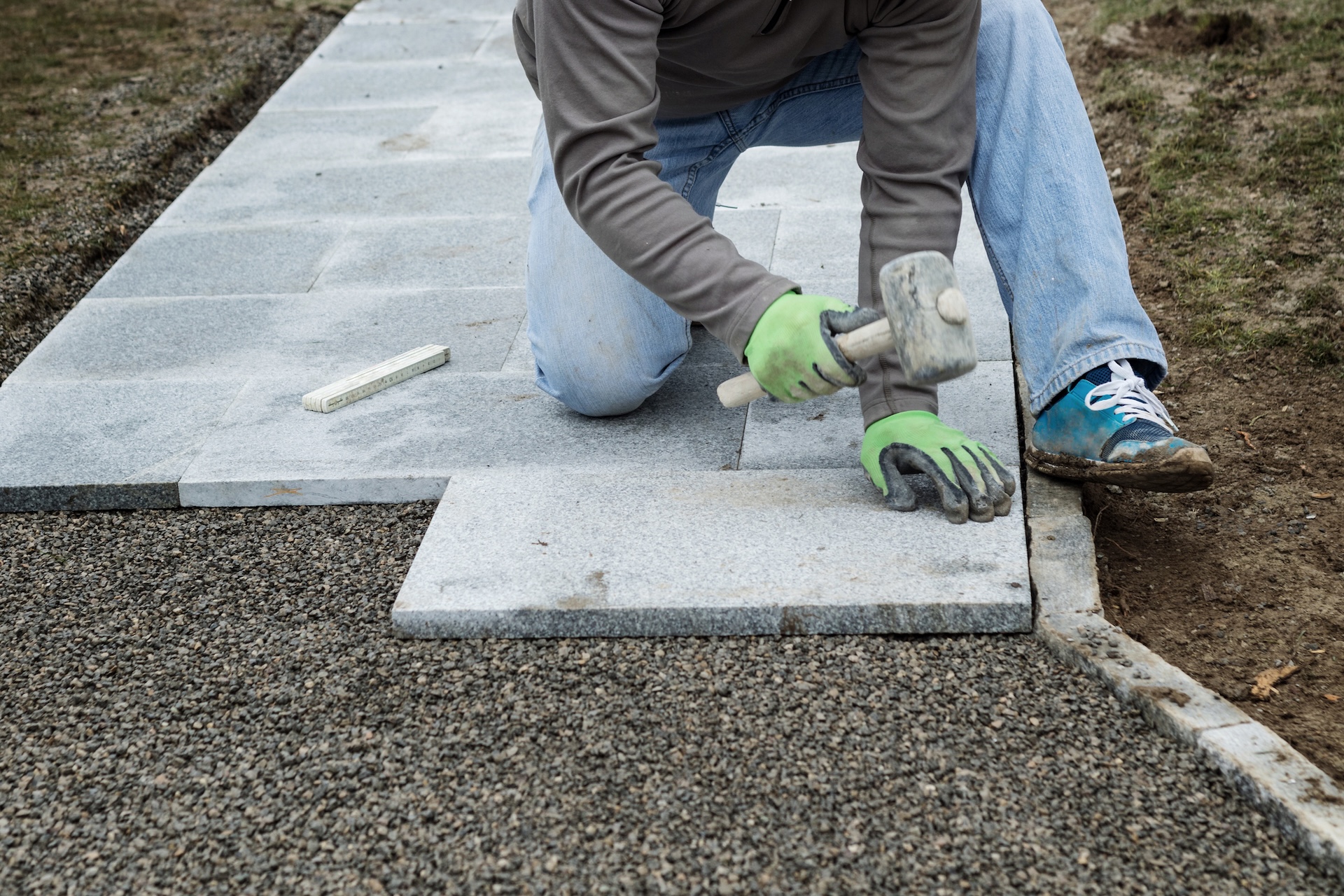 worker hammering the stone plates to install footpath at garden worker hammering the stone plates to install footpath at garden